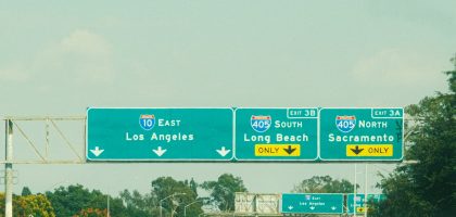 Highway signs with directions to Los Angeles, Long Beach, and Sacramento on a clear day.