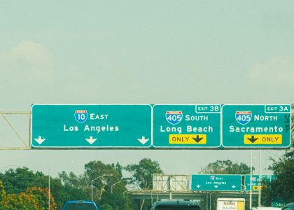 Highway signs with directions to Los Angeles, Long Beach, and Sacramento on a clear day.